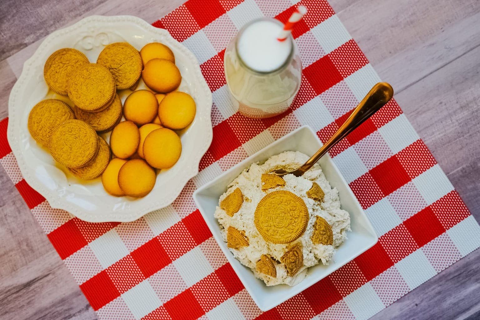 picture of cheesecake dip with carrot cake Oreos and milk on a checkered tablecloth